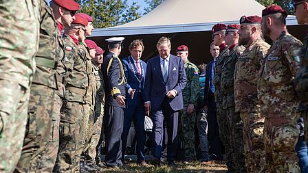 Burgemeester Rene Verhulst en koning Willem-Alexander lopen door een haag van militairen. 