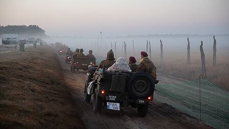 Ne-enactment militairen in een voertuig arriveren op de Ginkelse Heide waar nog ochtendmist hangt. 