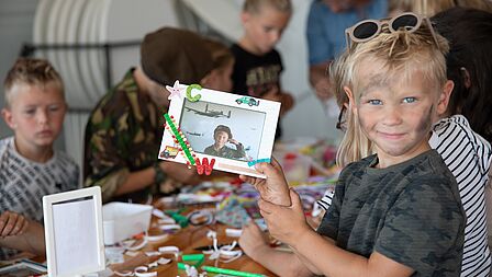 Een jonge bezoeker toont zijn ingelijste foto in militaire outfit. 